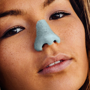 Woman with blue Nöz, suncreen on her nose